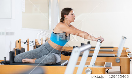 Active woman doing pilates exercises on pilates workout machines 129455466