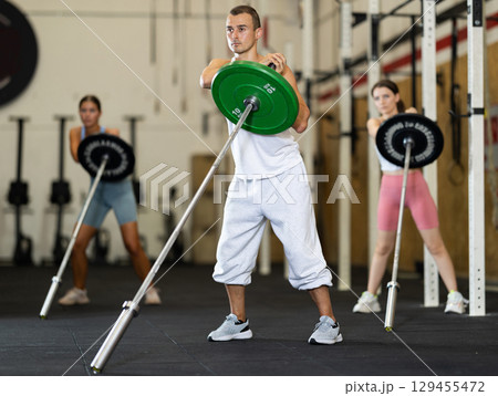 Young man training with barbell in gym Young man training with barbell in gym 129455472