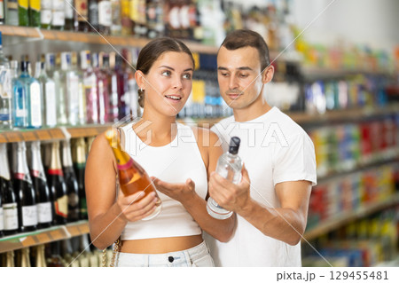 Married couple chooses alcoholic drinks in supermarket - vodka, champagne or whiskey 129455481