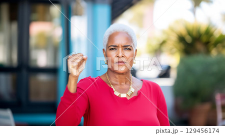 Black mature woman with raised fist of empowerment, strength and women solidarity, International Womens Day, Black History Month concept 129456174
