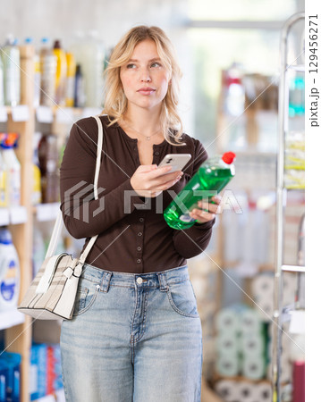 Before making purchase, girl buyer scan QR code on packaging of dishwashing soap Before making purchase, girl buyer scan QR code on packaging of dishwashing soap 129456271
