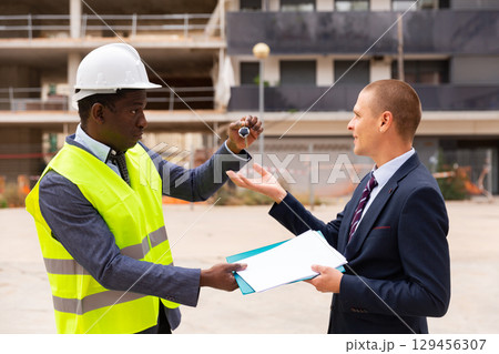 Man reciveing keys to new apartment from engineer Man reciveing keys to new apartment from engineer 129456307