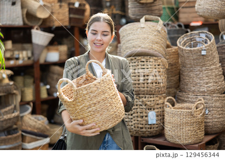 Positive woman looking for handmade wickerwork in home decor shop Positive woman looking for handmade wickerwork in home decor shop 129456344