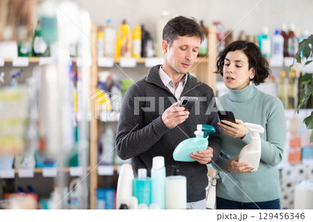 Husband and wife scan cleaning sprays on phone 129456346