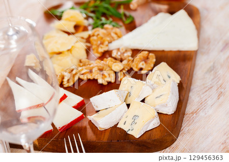 Cheese platter with honey, walnuts, arugula served on wooden board 129456363