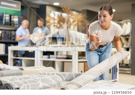Young woman choosing carpet in building store Young woman choosing carpet in building store 129456650