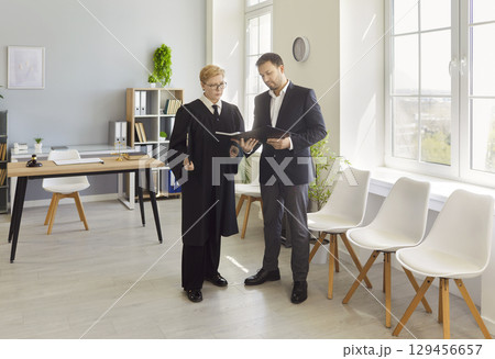 Woman judge talking to lawyer in office with legal documents discussing legislation issues. Woman judge talking to lawyer in office with legal documents discussing legislation issues. 129456657