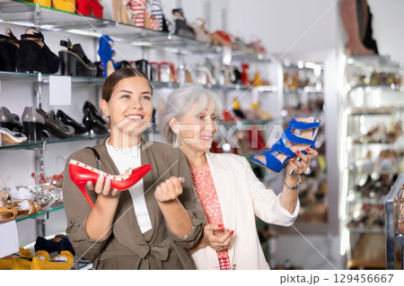 Two female customers choosing fashionable high heel shoes in shoe store Two female customers choosing fashionable high heel shoes in shoe store 129456667