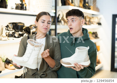 Couple man and woman choosing winter boots in store 129456854