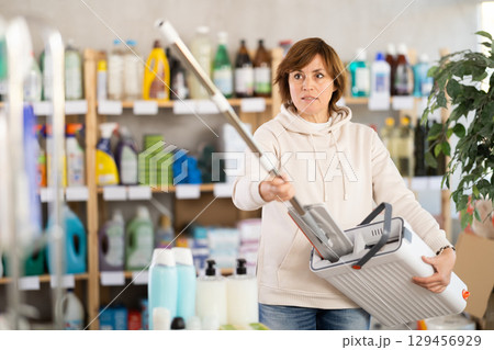 Adult woman chooses mop in store 129456929