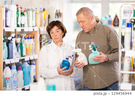 Couple man and woman choosing cleaning spray in store Couple man and woman choosing cleaning spray in store 129456944