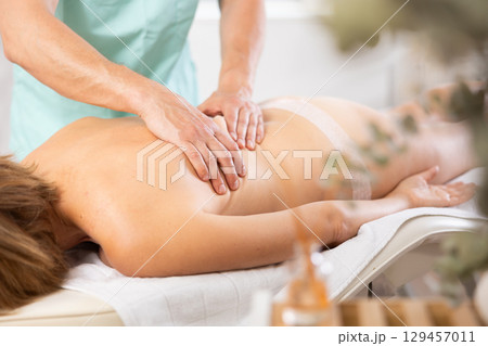 Woman dressed in tango panties receives massage of shoulder area, close-up, male masseur Woman dressed in tango panties receives massage of shoulder area, close-up, male masseur 129457011