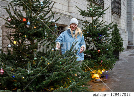 Female traveler enjoying Christmas lights and trees in Tallinn street. Christmas market atmosphere Female traveler enjoying Christmas lights and trees in Tallinn street. Christmas market atmosphere 129457012