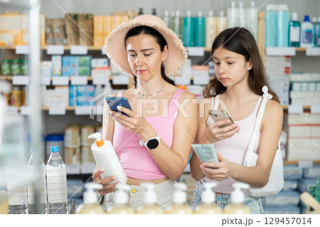 Woman with child scanning package with sunscreen in pharmacy 129457014