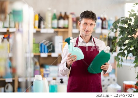 Middle-aged salesman offering detergent and spray in retail store Middle-aged salesman offering detergent and spray in retail store 129457027