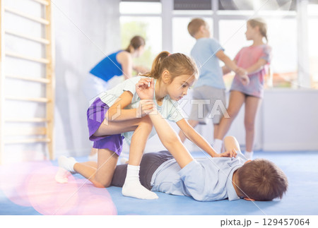 Girls and boys of performing protection with wring hands during training in self-defense 129457064