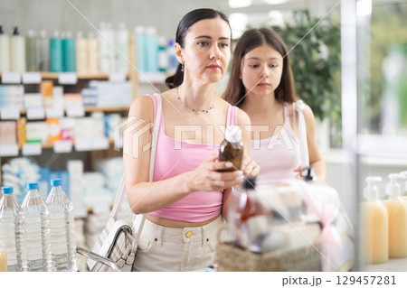 Mother and daughter choosing cough syrup at the pharmacy 129457281