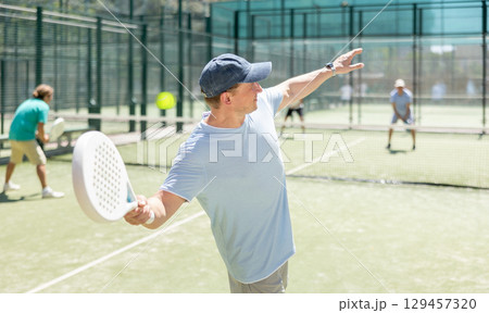 Adult men playing padel against two men 129457320