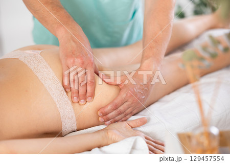 Woman lies and enjoys during anti-cellulite massage in buttocks 129457554
