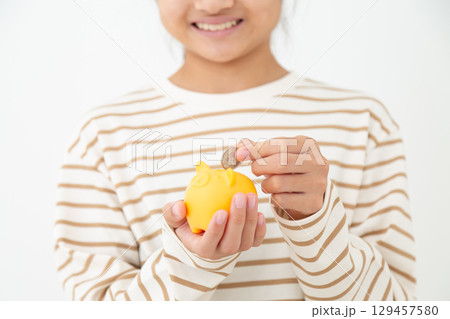 豚の貯金箱を持つ中学生の女の子 129457580
