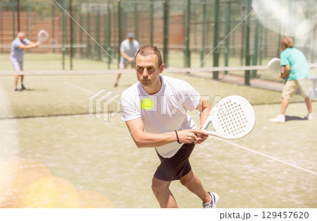 Adult and young men playing padel against two men 129457620