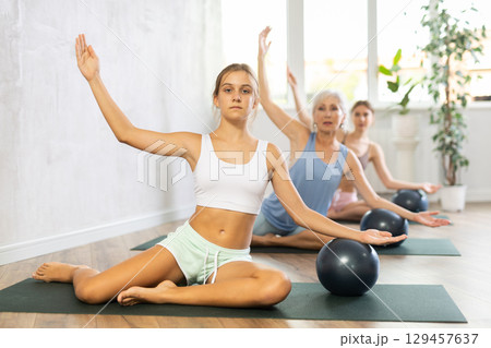 Teenage girl doing pilates with soft ball in group Teenage girl doing pilates with soft ball in group 129457637