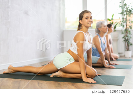 Womens different ages practicing yoga lesson at sport club Womens different ages practicing yoga lesson at sport club 129457680