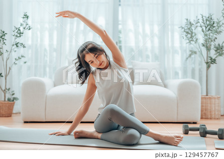 Happy young Asian woman practicing yoga and shoulder stretching at home Happy young Asian woman practicing yoga and shoulder stretching at home 129457767