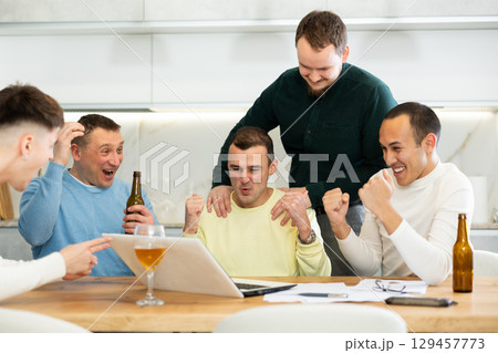 Happy male friends exulting after successful virtual investment 129457773