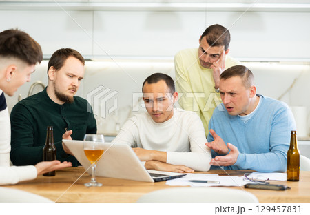Group of men comforting distressed friend at computer at home 129457831
