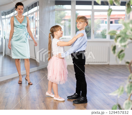 Tween boy and girl performing waltz in pair in dance hall 129457832