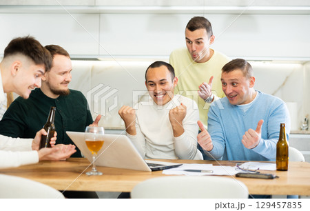Happy male friends exulting after successful virtual investment Happy male friends exulting after successful virtual investment 129457835