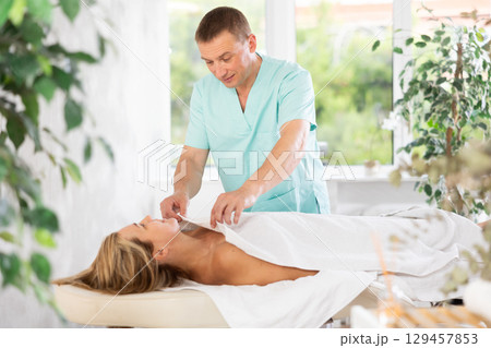 Male therapist covers woman client with white terry sheet after relaxing massage procedure Male therapist covers woman client with white terry sheet after relaxing massage procedure 129457853