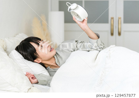 目覚まし時計を見て驚くびっくりする若いアジア人女性(寝坊,遅刻,寝過ごす) 目覚まし時計を見て驚くびっくりする若いアジア人女性(寝坊,遅刻,寝過ごす) 129457877