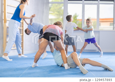 Boys and girls in gym perform basic elements of krav maga self-defense system. Boys and girls in gym perform basic elements of krav maga self-defense system. 129457893