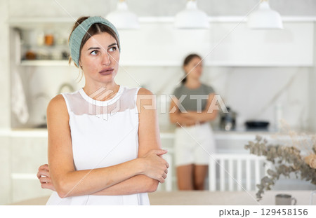 Serious woman is standing in kitchen and thinking about something 129458156