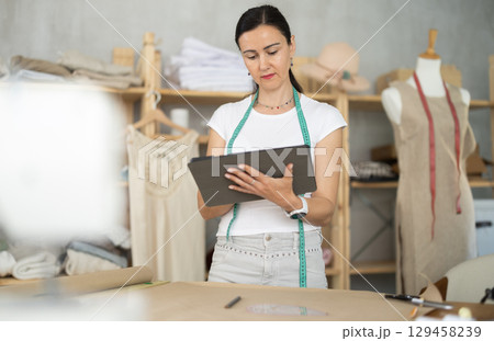 Woman dressmaker makes pattern using tablet 129458239