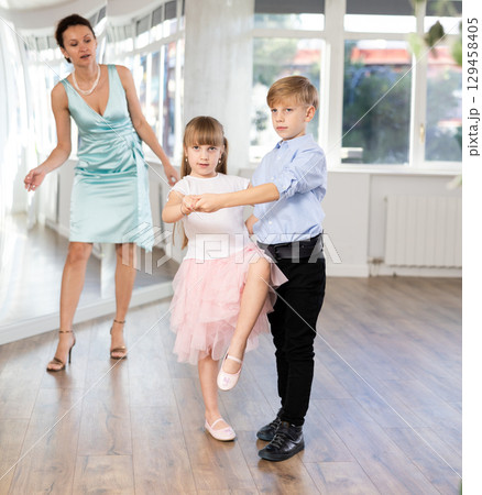 Kids learning cha-cha with female dance instructor in choreography studio Kids learning cha-cha with female dance instructor in choreography studio 129458405