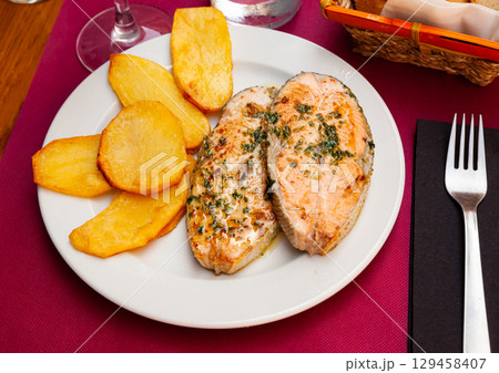 Fried salmon steak served with baked potatoes Fried salmon steak served with baked potatoes 129458407