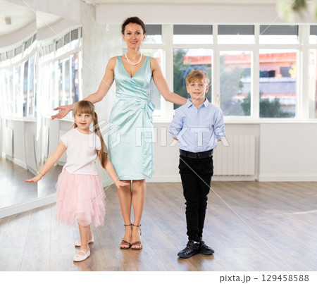 Female choreography teacher stands next to couple of teen boy and girl students Female choreography teacher stands next to couple of teen boy and girl students 129458588