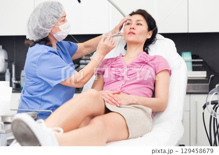 Female client receiving cosmetic injection from professional cosmetician closeup 129458679