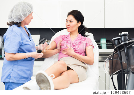 Woman consulting with cosmetologist about breast augmentation procedures 129458697