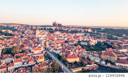 A breathtaking view of Prague at sunrise reveals the city's iconic skyline. The Vltava river gracefully flows alongside historic buildings, with the Charles Bridge and castle in the background. A breathtaking view of Prague at sunrise reveals the city's iconic skyline. The Vltava river gracefully flows alongside historic buildings, with the Charles Bridge and castle in the background. 129458946