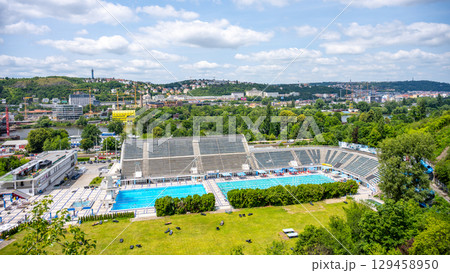 People relax and swim at Podoli Swimming Pool in Prague on a warm summer day. The vibrant atmosphere reflects the joys of summer in Czechia. A beautiful location for leisure and fun. People relax and swim at Podoli Swimming Pool in Prague on a warm summer day. The vibrant atmosphere reflects the joys of summer in Czechia. A beautiful location for leisure and fun. 129458950