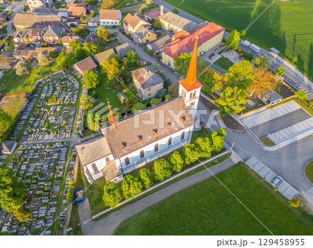 Church of Saint Mary Magdalene stands prominently in Bohutin, surrounded by a quaint village and lush greenery. Its tall spires and historical architecture attract visitors and locals alike. 129458955
