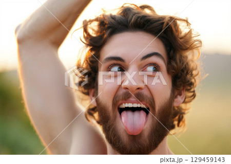 Joyful Young Man Making Funny Face Outdoors During Sunset Near Nature 129459143