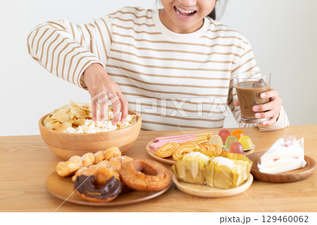 たくさんのお菓子を食べる中学生の女の子 たくさんのお菓子を食べる中学生の女の子 129460062