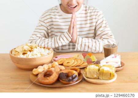 たくさんのお菓子を見て喜ぶ中学生の女の子 129460170