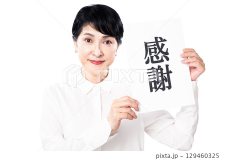 感謝と書かれた紙を持ち微笑む白いシャツを着たシニア女性 感謝と書かれた紙を持ち微笑む白いシャツを着たシニア女性 129460325