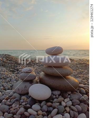 Balanced stone stacks in a serene style in gray and white colors representing tranquility against a calm ocean sunset 129461274